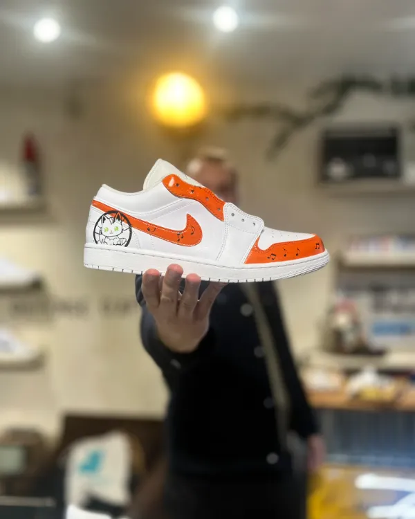 Une paire de sneakers blanches peinte en orange pendant un atelier custom Maison Sneakers