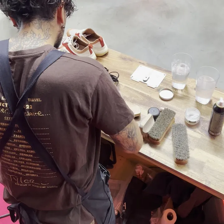 L'équipe Maison Sneakers nettoie des paires sur un stand, vue de dos